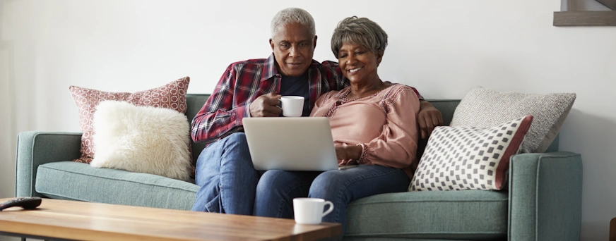 Life Assure Senior Couple Sitting On Sofa At Home Hero